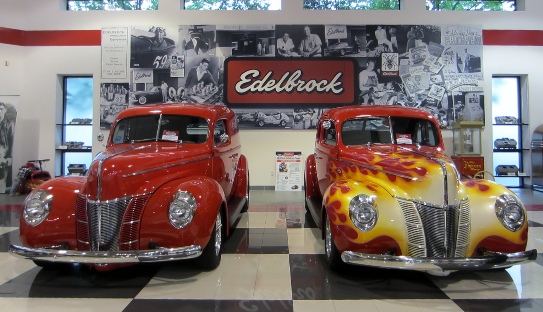 2 red hot rods parked in a show shop at Edelbrock