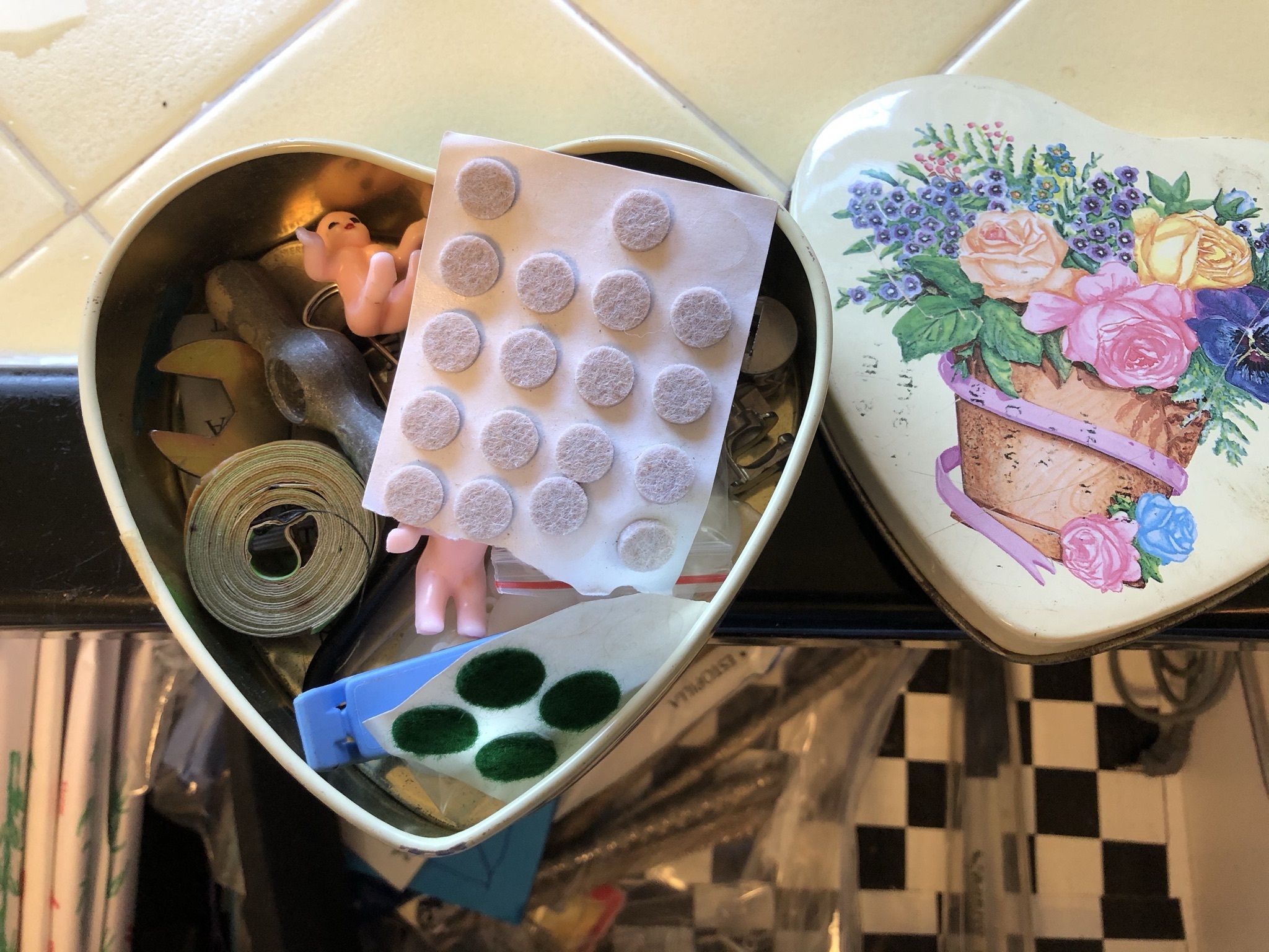 A metal tin of odds and ends in the kitchen junk drawer.