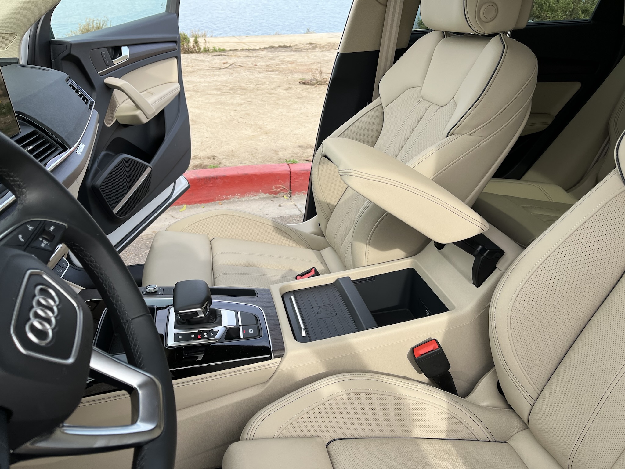 The wireless phone charging pad on a shelf below the center armrest.