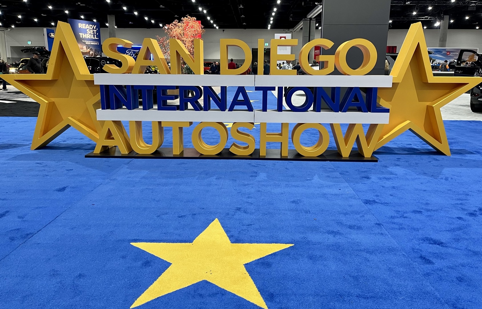 The auto show "selfie" icon on blue carpet with a big gold star