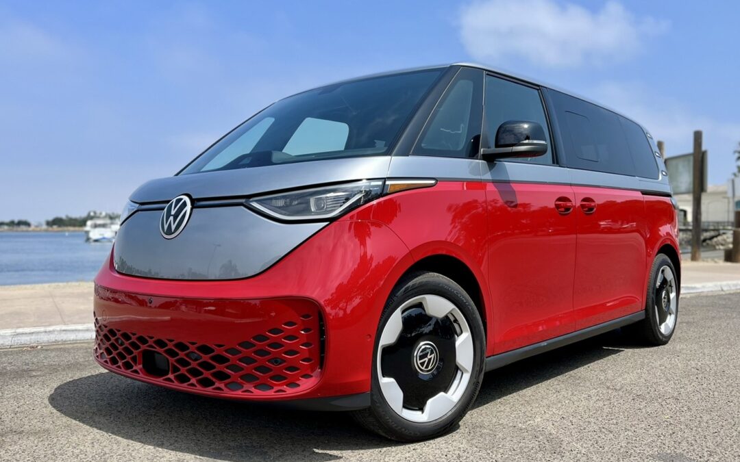 A silver and red VW ID Buzz electric minivan, amid a blue sky background