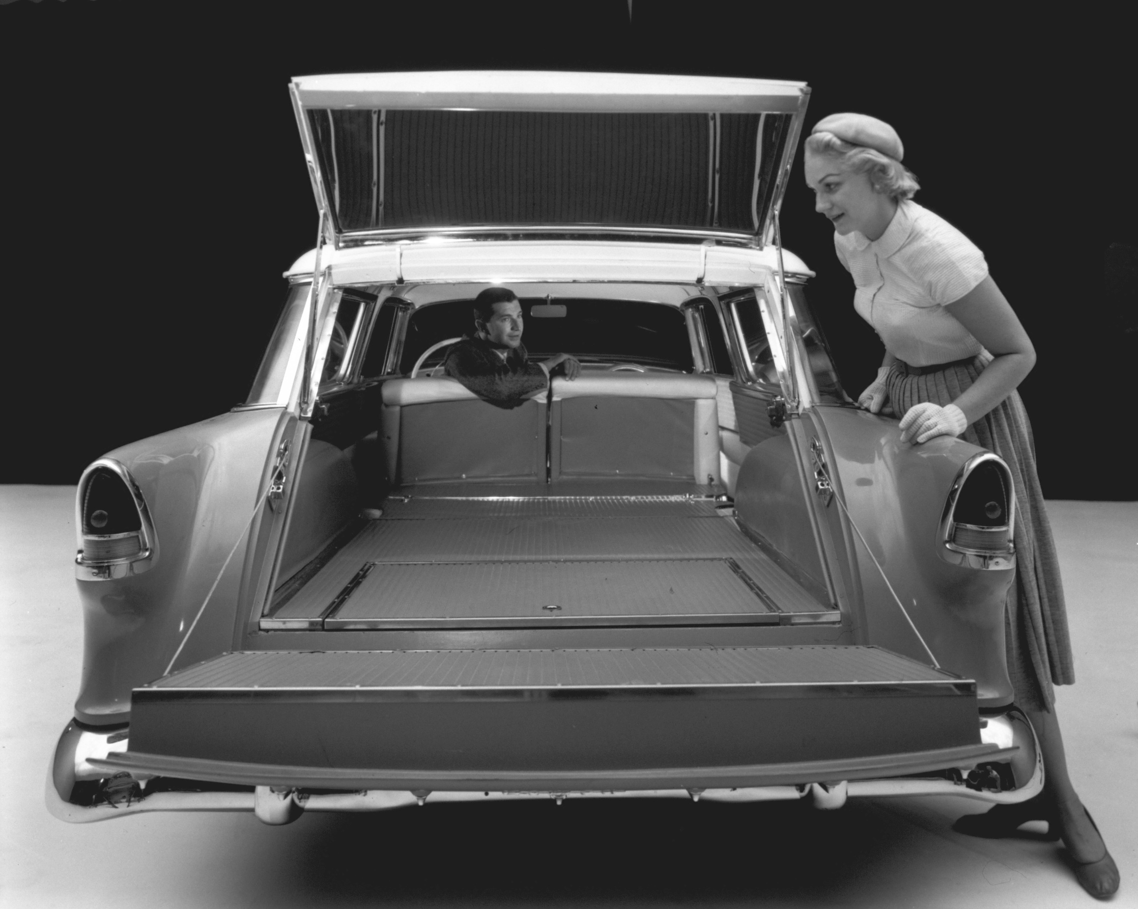 A female model wearing white gloves looks into the Nomad cargo area of the Chevrolet Bel Air Nomad_Cargo area with 