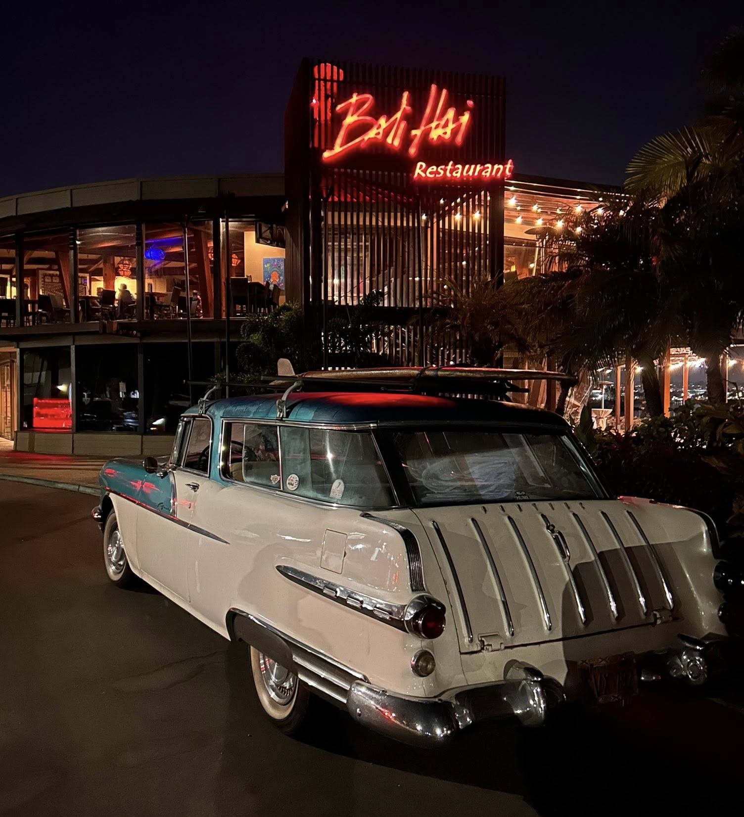 A color nighttime image of Norm Daniels' 1956 Safari in Vista Turquoise and Nimbus White. He calls his wagon the “Safari Tiki Wagon O Fun.”