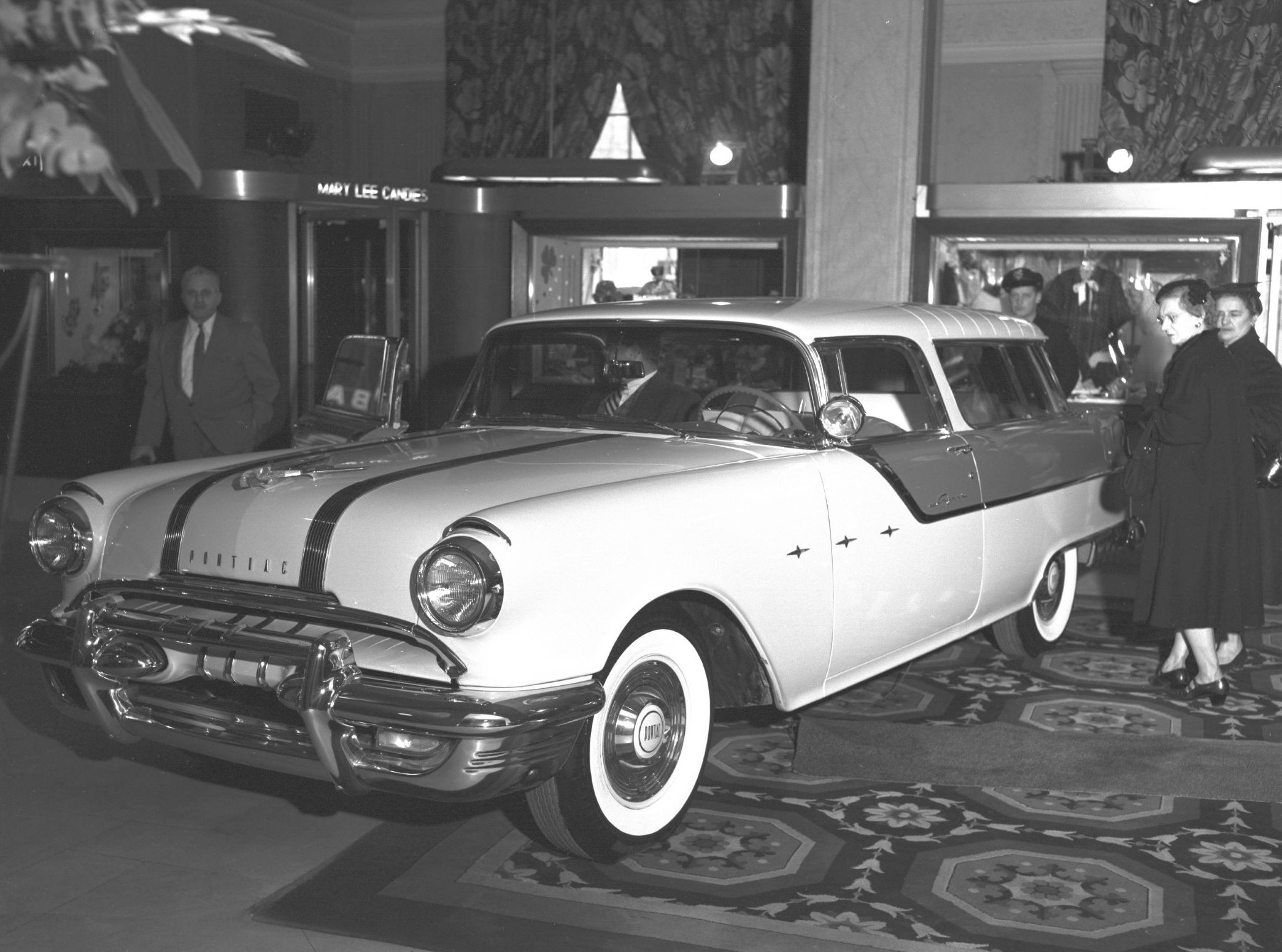 A black and white image of a salon auto show showing the first 1955 Pontiac Safari two door wagon