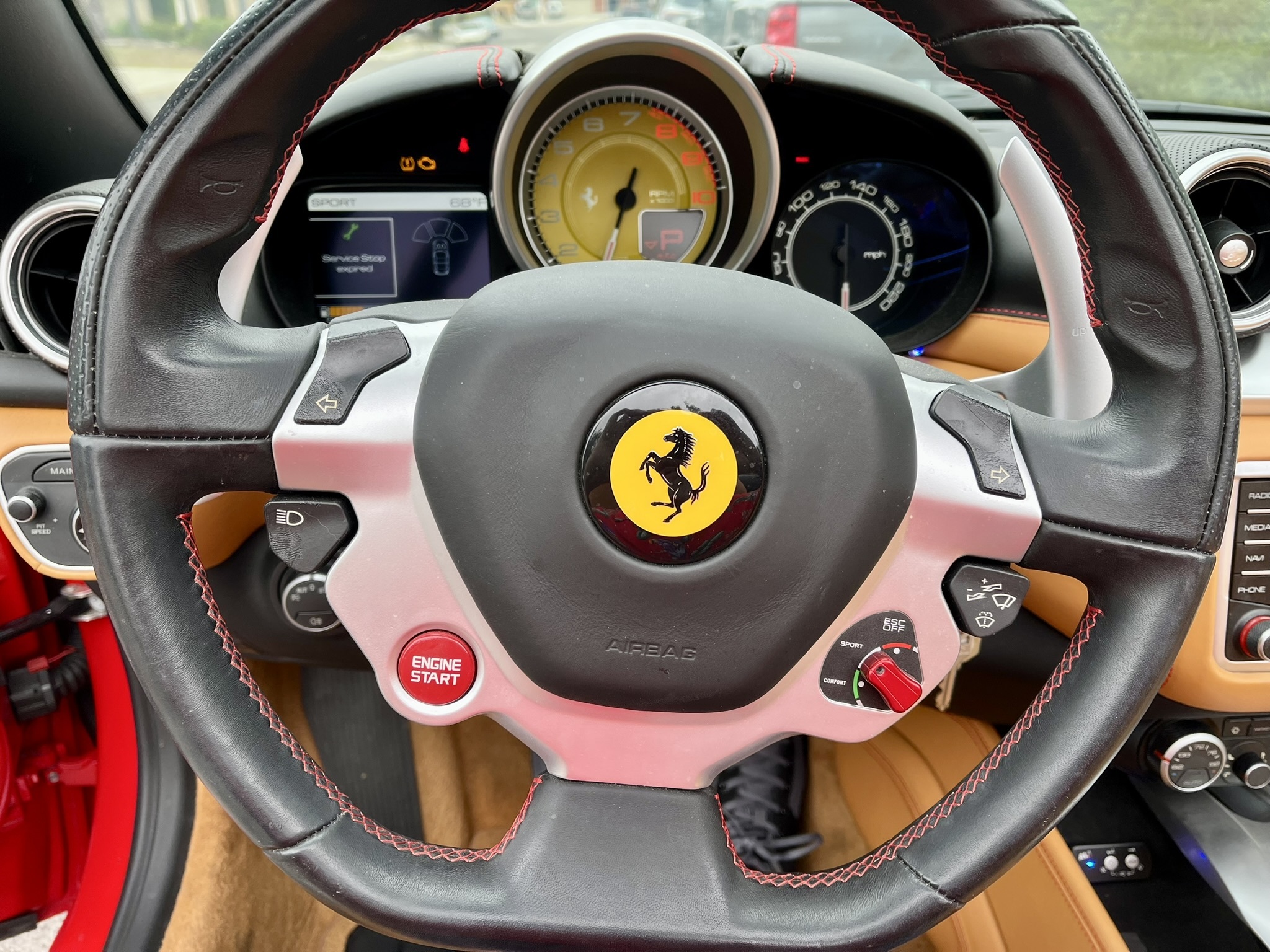 The red engine-start button on the steering wheel.