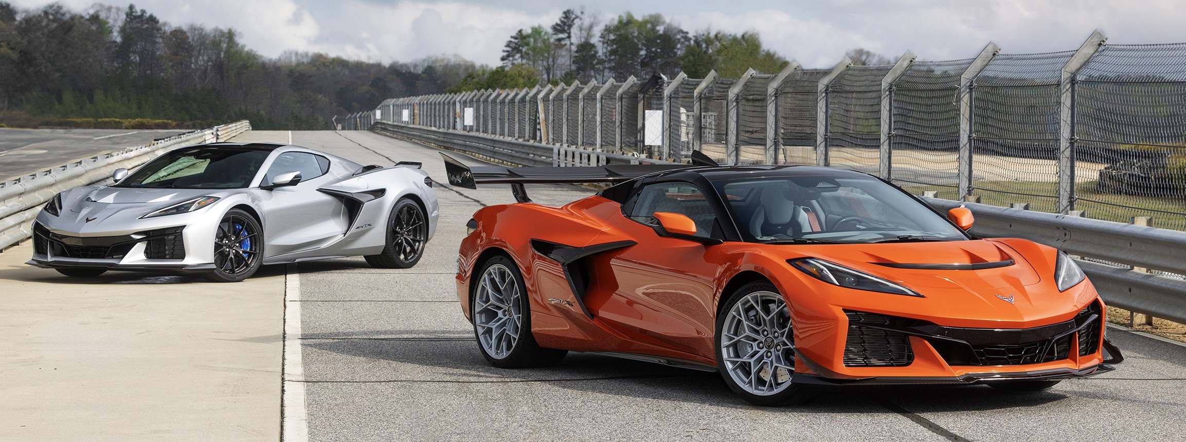 2 Corvette ZR1x models posed on a rack track, one car is orange, the other is silver