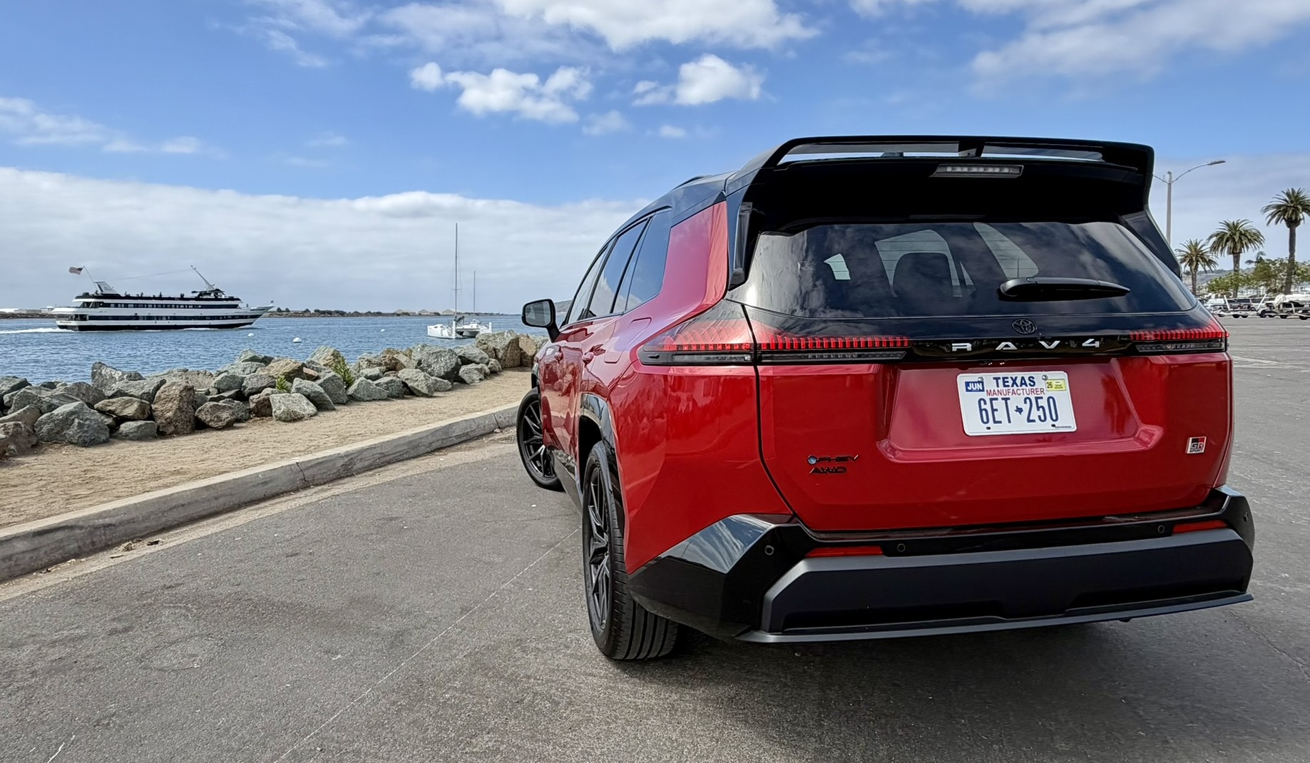 Looking at a rear three quarter view of GR Sport parked along the marina with a sailboat in the background